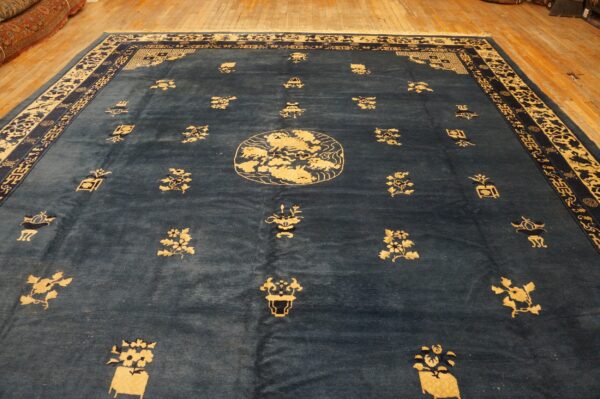 Deep blue rug with gold traditional patterns, central medallion, and wide borders on hardwood flooring.