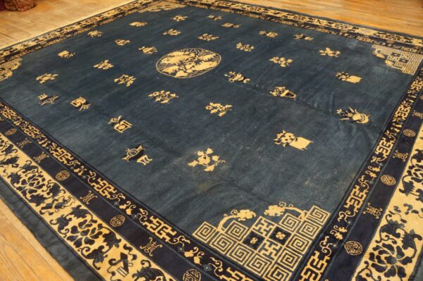 Large deep blue rug with scattered gold motifs and intricate multi-layered borders on wood floorboards.