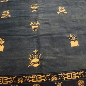 Dark blue rug featuring scattered gold floral designs and a navy border with geometric patterns.