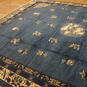 Blue rug with cream and dark blue geometric borders and scattered motifs rests on wood planks.