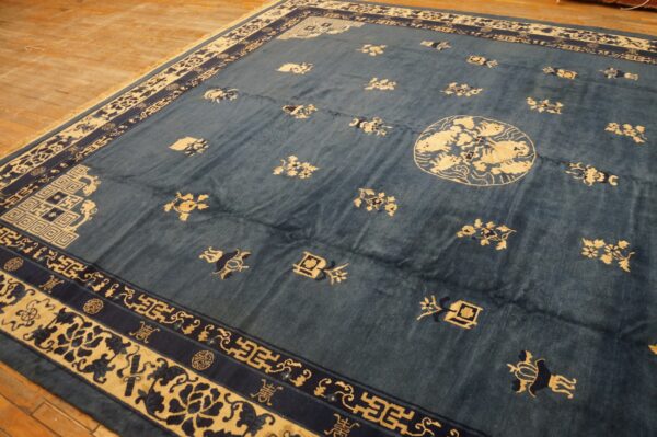 Blue rug with cream and dark blue geometric borders and scattered motifs rests on wood planks.