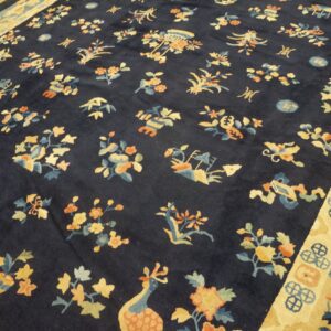 Navy blue rug featuring stylized gold, orange, and teal floral motifs surrounded by a thick yellow border.