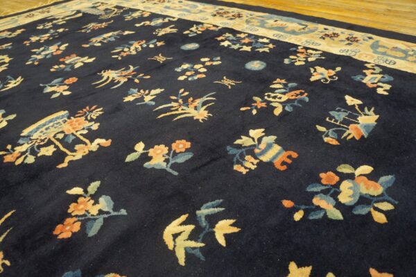 Navy high-pile rug with colorful botanical designs and a wide tan border on a hardwood floor.
