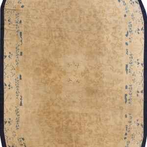 Oval rug with a tan field, subtle tone-on-tone scrollwork pattern, and a wide dark navy border.