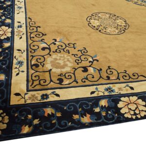 Close view of a tan rug with an elaborate navy blue border featuring cream and peach floral motifs.