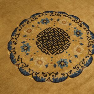 Mustard yellow rug featuring a circular medallion with blue florals and a black key pattern.