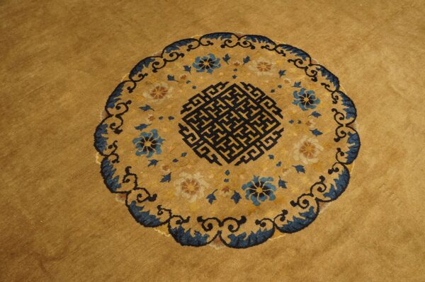 Mustard yellow rug featuring a circular medallion with blue florals and a black key pattern.