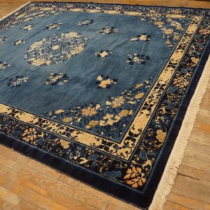 Blue rug with central medallion and floral borders lies on distressed wood plank flooring.