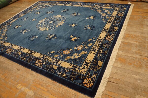 Blue rug with central medallion and floral borders lies on distressed wood plank flooring.