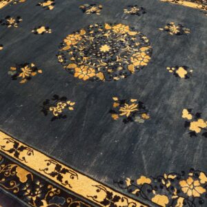 A dark blue rug with scattered gold floral motifs and a central medallion sits on a wood floor.