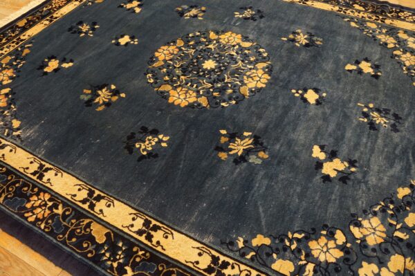 A dark blue rug with scattered gold floral motifs and a central medallion sits on a wood floor.