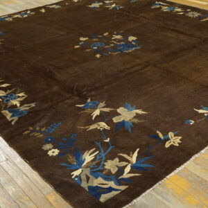 Dark brown rug featuring a blue and beige floral and bird pattern border on rough wood flooring.