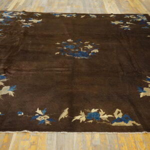 Espresso rug with blue and tan floral and bird motifs covers a bright wooden plank floor.