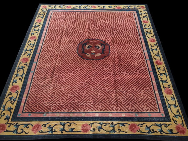 Red geometric rug with a dark central medallion and wide gold borders featuring blue scrolling floral motifs.