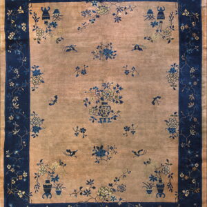Rectangular rug with a tan field and navy border, patterned with ornate blue and pale yellow florals.