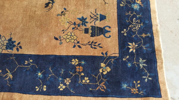 Antique chinese - peking room size wool gray rug 4 Close view of a tan rug with a navy border featuring detailed gold and blue floral vines.