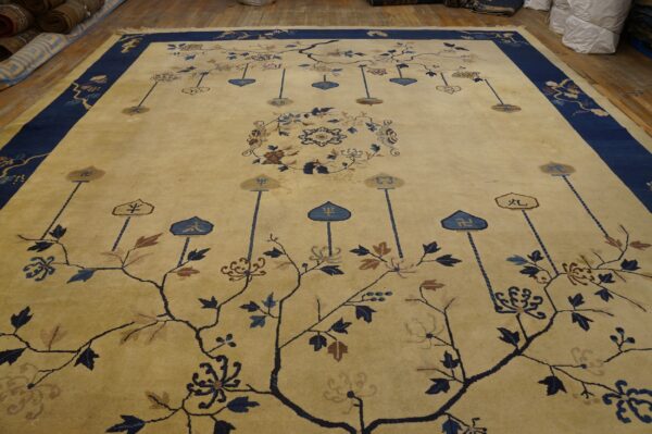 Pale gold rug with a navy blue border and an intricate blue and brown botanical pattern on wood floors.