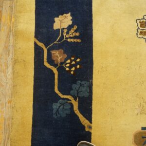 Low-pile yellow rug displaying floral motifs against a navy blue vertical stripe on wood planks.