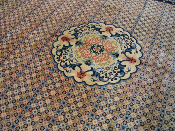 Ornate rug detail showing a dense blue and pink repeating pattern and a large scalloped medallion.