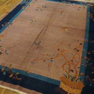Mauve low-pile rug with colorful floral and bird patterns bordered by navy and teal on wood planks.