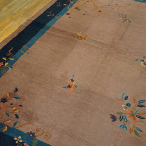 Close-up of a taupe rug with scattered floral patterns and navy/teal borders on yellow hardwood floor.