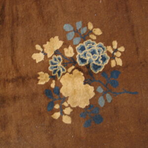 Plush brown rug featuring a stylized floral motif in light beige and multiple shades of blue.