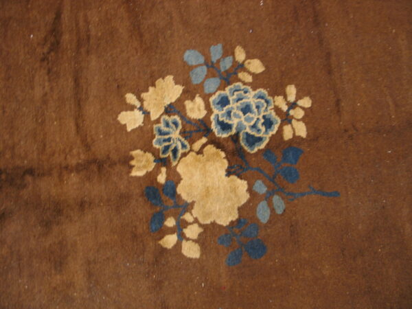 Plush brown rug featuring a stylized floral motif in light beige and multiple shades of blue.