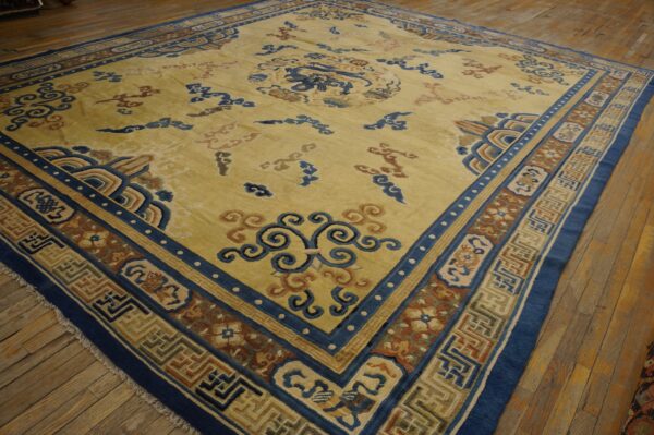Large yellow rug with intricate blue, brown, and tan stylized patterns rests on a distressed wood floor.