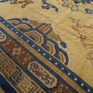 Yellow field rug with complex blue, rust, and tan geometric borders and stylized cloud motifs.