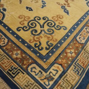 Traditional rug corner displaying a yellow field and multi-colored blue and brown patterned border on wood floor.