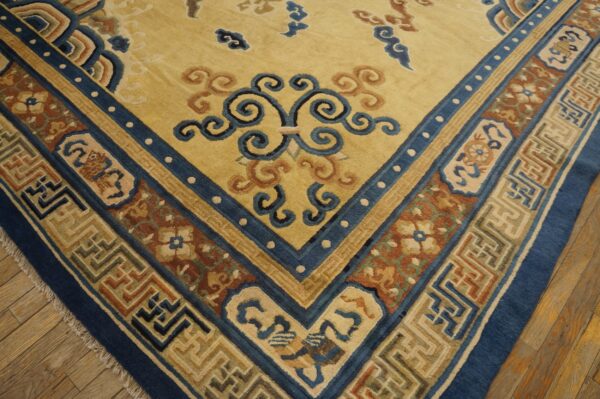 Traditional rug corner displaying a yellow field and multi-colored blue and brown patterned border on wood floor.