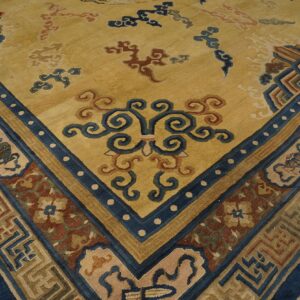 Golden yellow rug corner featuring complex blue and rust borders and scattered stylized cloud patterns.