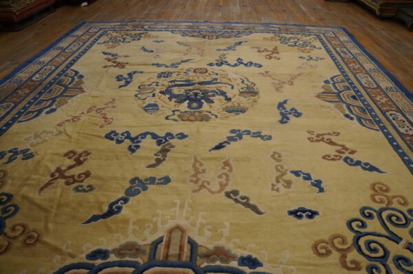 Yellow field rug featuring a detailed blue dragon medallion, rust clouds, and a complex patterned border on wood floor.