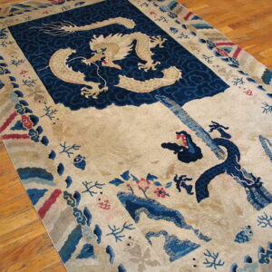Cream rug with a beige dragon on indigo clouds and multicolored borders, displayed on wood floors.