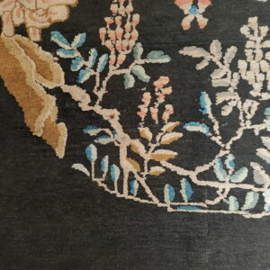 Dark field rug detail showing ornate vines and stylized flowers in cream, tan, pink, and light blue.