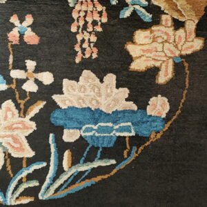 Detailed view of a plush, dark rug with floral patterns in cream, blue, and salmon.