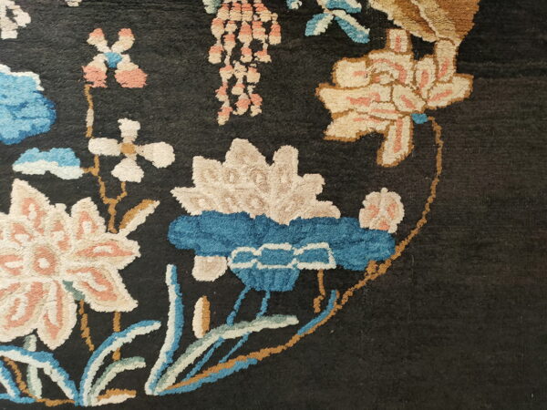 Detailed view of a plush, dark rug with floral patterns in cream, blue, and salmon.