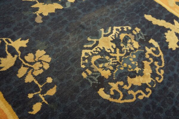 Close-up of a low pile rug featuring golden yellow floral motifs on a textured dark blue background.