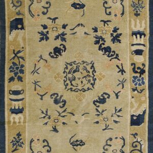 A tan rug with navy blue and pink traditional floral and scrollwork designs in the field and borders.