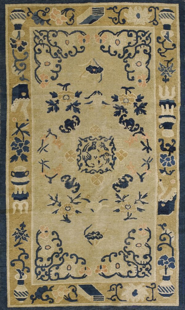A tan rug with navy blue and pink traditional floral and scrollwork designs in the field and borders.