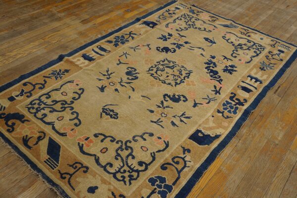 Angled view of a tan and blue patterned rug featuring coral flowers on distressed wood planks.