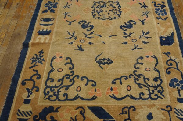 A tan rug featuring stylized navy and peach floral designs rests upon distressed wooden flooring.