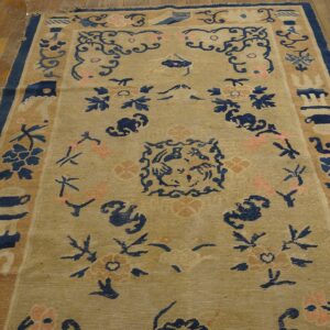 Beige rug with deep blue and soft pink traditional patterns covers distressed wood plank flooring.