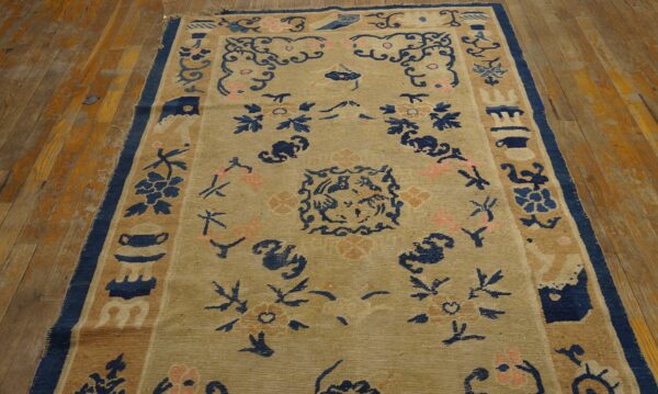 Beige rug with deep blue and soft pink traditional patterns covers distressed wood plank flooring.