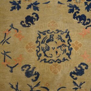 Low-pile tan rug featuring stylized navy blue and coral floral patterns and a detailed central design motif.