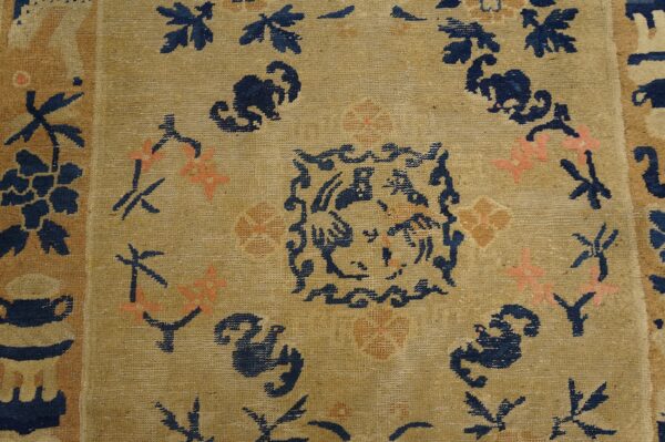 Low-pile tan rug featuring stylized navy blue and coral floral patterns and a detailed central design motif.