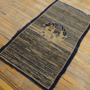 Navy and tan striped rug featuring a circular blue motif is laid diagonally on distressed wood plank flooring.