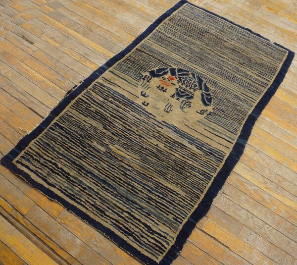 Navy and tan striped rug featuring a circular blue motif is laid diagonally on distressed wood plank flooring.