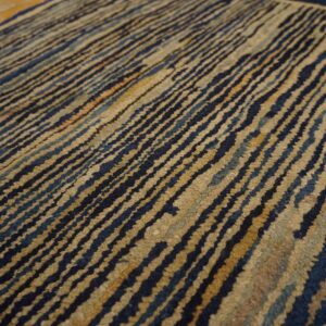 Distressed rug detail featuring diagonal wavy dark blue and tan textured stripes.