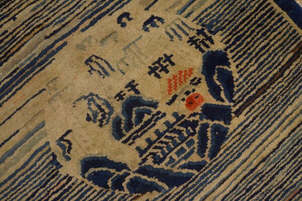 Coarse pile rug detail showing blue and tan striped borders surrounding a central abstract motif with red spots.
